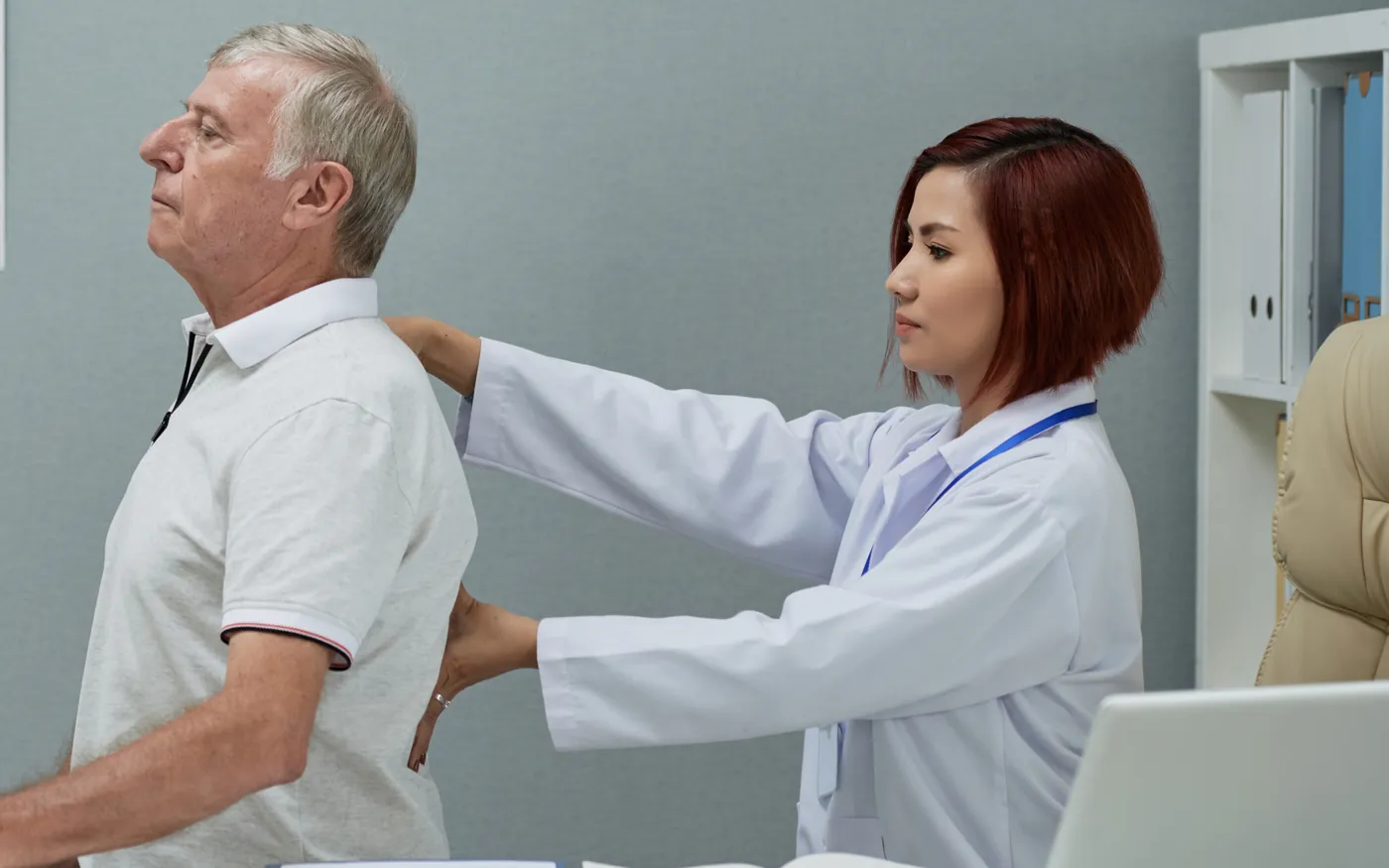 Médica examinando a coluna de um paciente durante a consulta
